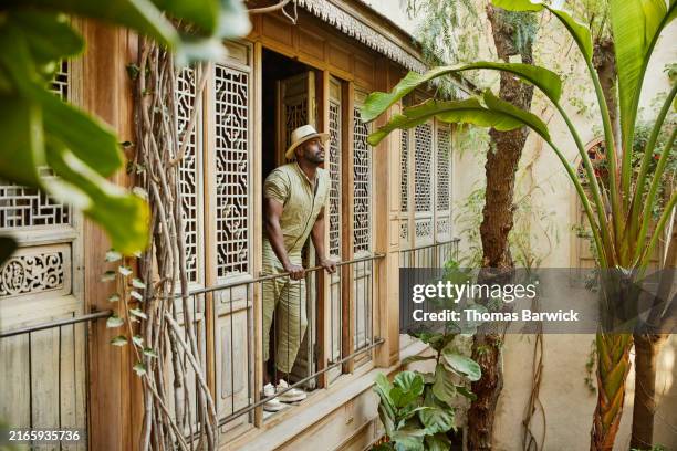 wide shot man looking out to garden courtyard from hotel suite balcony - geographical locations stock pictures, royalty-free photos & images