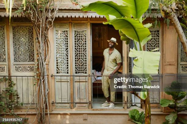 wide shot man looking at garden courtyard from hotel suite balcony - balcony stock pictures, royalty-free photos & images