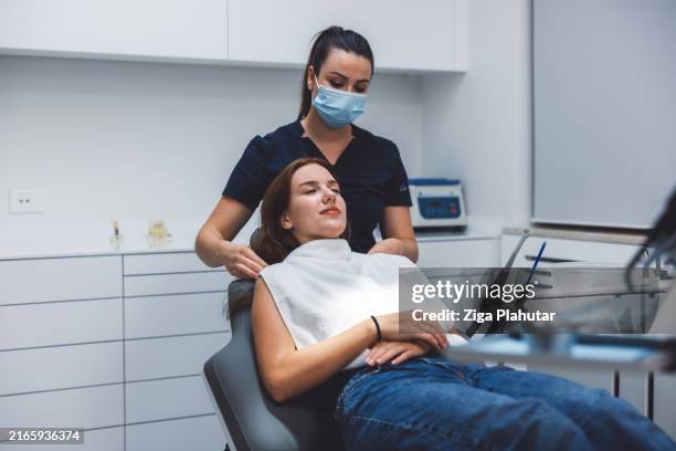 patient relaxing in dental chair with professional assistance - tandartsstoel stockfoto's en -beelden