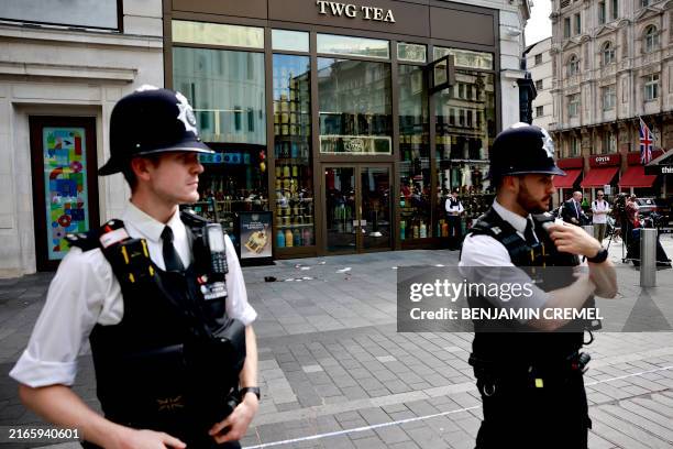 Photograph taken on August 12, 2024 shows police officers standing by a cordoned off area in Leicester square, London. A woman and an 11-year-old...