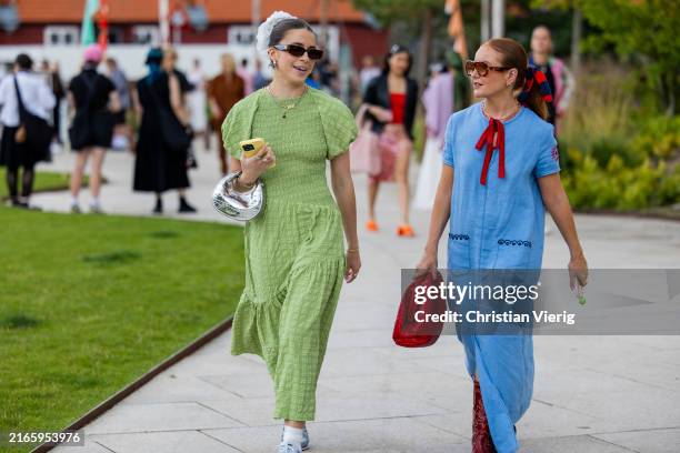 Charlotte Olivia wears green dress, silver bag & Rebecca Olivia wears bow, blue dress, red Bottega Veneta bag outside Marimekko during day four of...