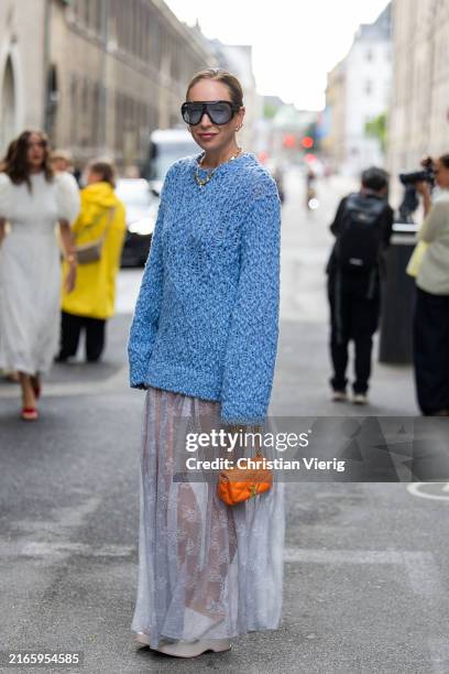 Sonia Lyson wears blue oversized jumper, orange bag, transparent white skirt, necklace, sunglasses outside Rotate during day four of the Copenhagen...