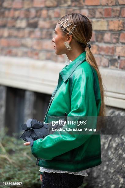 Rita Montezuma wears green leather jacket, denim jeans, hair clips, green bag outside Rotate during day four of the Copenhagen Fashion Week SS25 on...