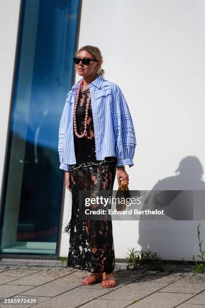 Guest wears black sunglasses, silver earrings, pink multi-colored necklaces, black sheer mesh lace maxi skirt, light blue white lined unbuttoned long...