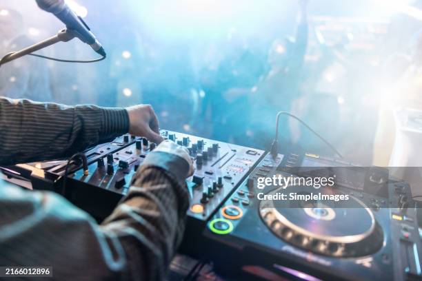 close up of dj hands controlling a music table in a night club. night club, nightlife concept. dj hands hold microphone and mixing dj remote. neon light. - dj imagens e fotografias de stock