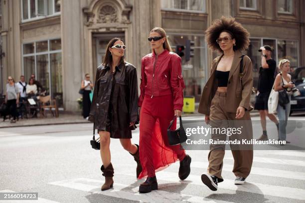 Julia Dalia wears brown suit, pants and blazer, black top, black bag and Converse sneakers and Alessa Winter wears red long skirt, red leather...