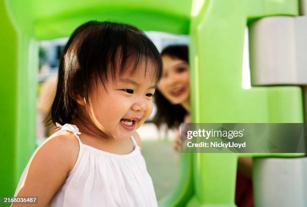 cheerful little girl enjoying playing on a toy house at playground - outdoor play equipment stock pictures, royalty-free photos & images