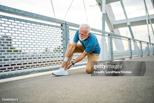 senior male runner touching ankle in pain - ankle stock pictures, royalty-free photos & images