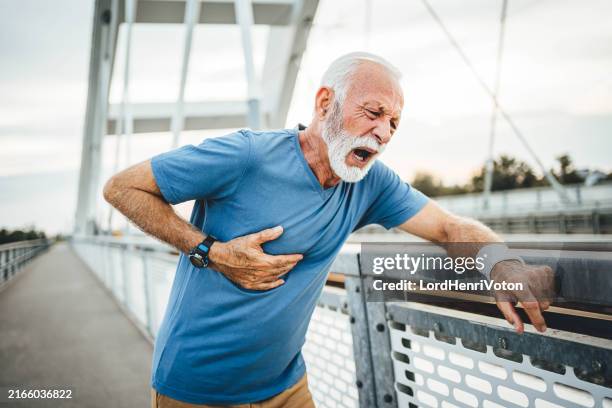 senior male runner touching his chest in pain - hartinfarct stockfoto's en -beelden
