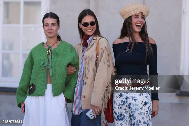 Fashion week guest is seen wearing green fabric jacket with two bows, a white skirt and a small brown crossbody bag. She is also wearing a black...
