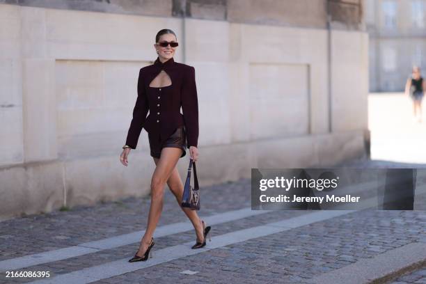 Nina Sandbech is seen wearing Bordeaux colored top with a high collar and cut outs with golden buttons and a corset top. She wears bordeaux colored...