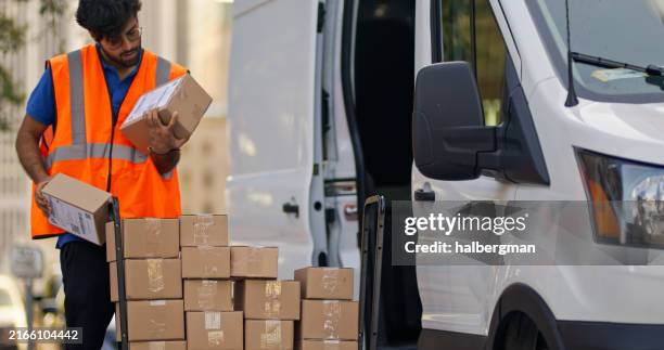 plano amplio medio del repartidor mirando las cajas cerca del carrito - paquete fotografías e imágenes de stock