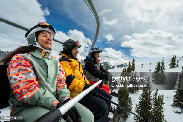frau schließt die augen und genießt die kalte brise beim fahren mit dem skilift mit freunden - colorado-westliche-bundesstaaten-der-usa stock-fotos und bilder