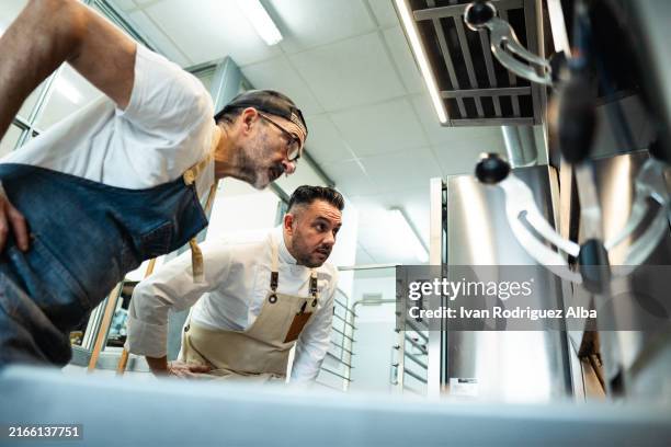 two bakers look at bread in the oven - food state stock pictures, royalty-free photos & images