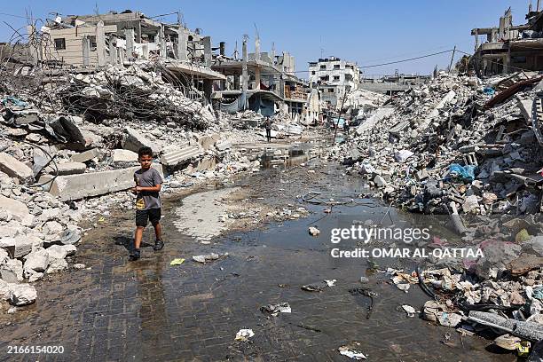 Boy walks through a puddle of sewage water past mounds of trash and rubble along a street in the Jabalia camp for Palestinian refugees in the...