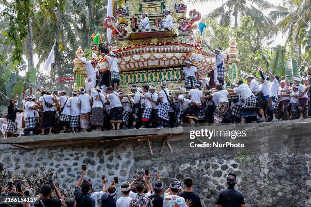 Balinese people are transporting a funeral tower which carries the remaining bodies of the deceased to the cemetery during a collective Balinese...