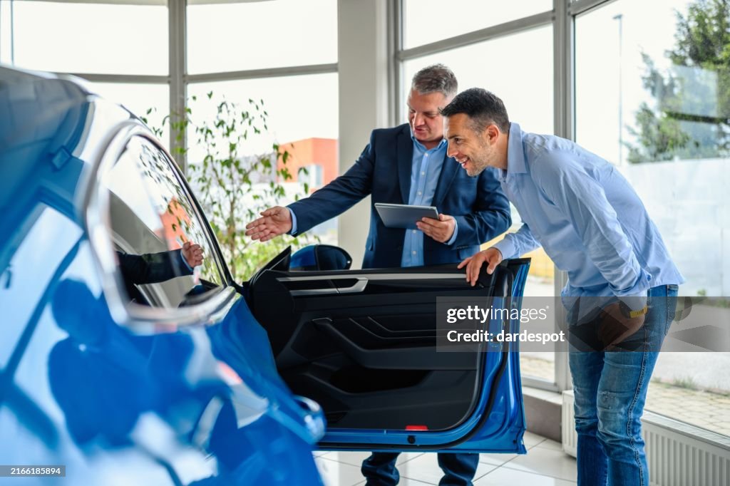 Salesman helping the male customer to choose a new car
