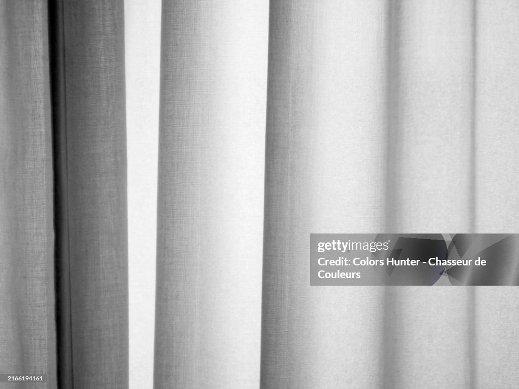 A wavy, backlit white curtain. Focus in the center of the photo.
Sunlight and shadow. Monochrome.
London, England, United Kingdom.