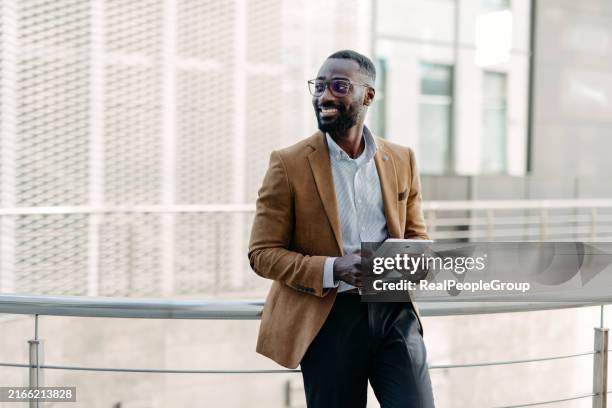 man leaning on railing with a tablet outdoors - black leader stock pictures, royalty-free photos & images