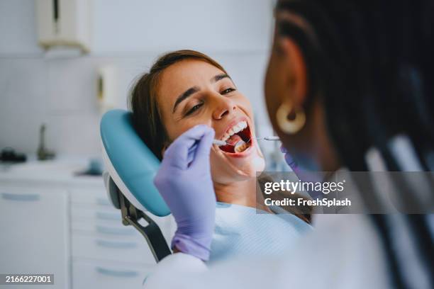 young woman receiving dental checkup from dentist in clinic - tandhälsa bildbanksfoton och bilder