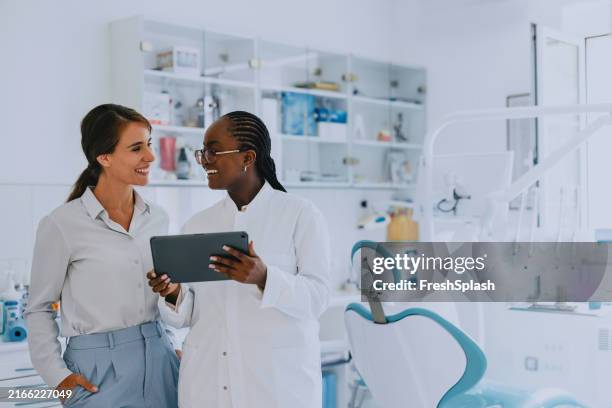 dentist and assistant discussing patient records in dental office - tandartspraktijk stockfoto's en -beelden