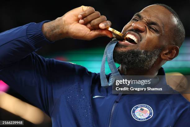 Gold medalist LeBron James of Team United States bites his medal while celebrating on the podium during the Men's basketball medal ceremony on day...