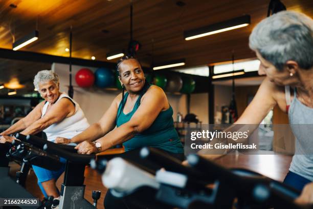 group of mature women practicing together in a luxury spa - fitnessapparatuur stockfoto's en -beelden