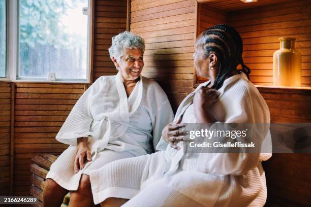 two mature women inside a sauna having conversations in a spa - alternative medicine stock pictures, royalty-free photos & images