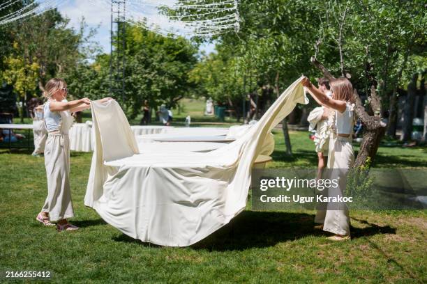 the wedding planning team is setting tablecloths on the tables for the wedding dinner. - banquet stock pictures, royalty-free photos & images