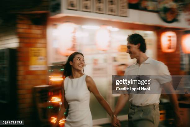 couple walking through tokyo backstreet alley with izakaya at night - activité romantique photos et images de collection
