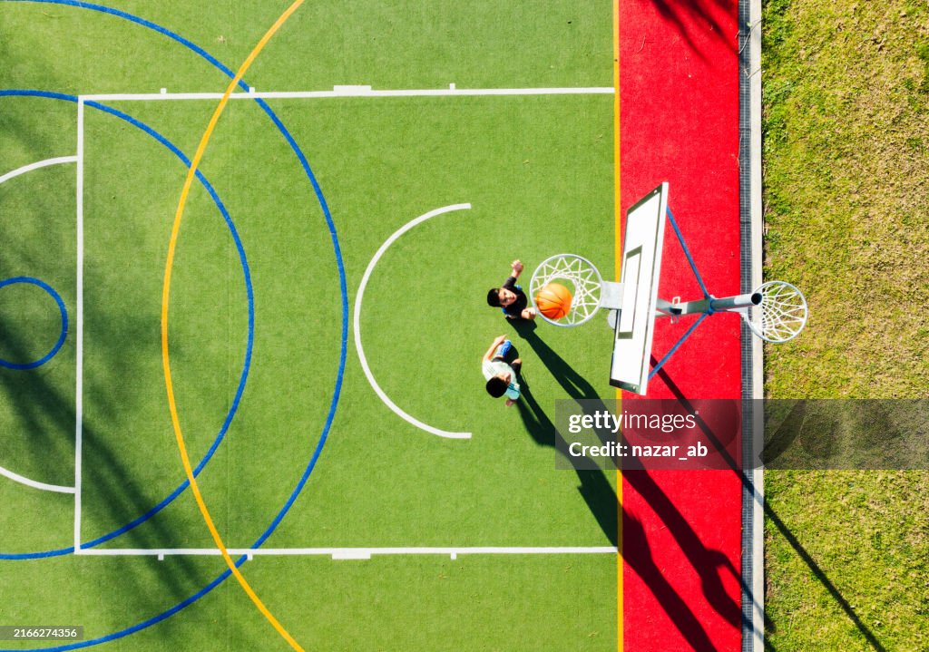 Competitive siblings playing basket ball, recreational pursuit.