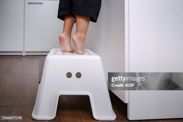 close-up of little girl legs on tiptoes at kitchen sink - lang lichaamslengte stockfoto's en -beelden