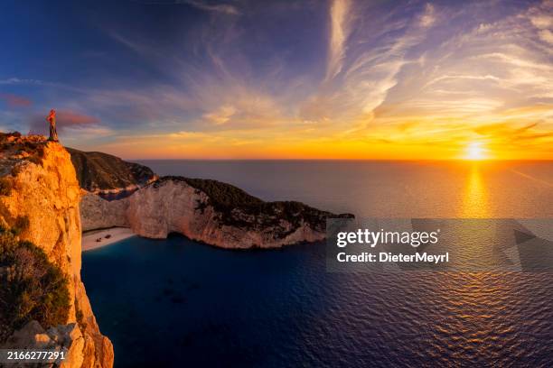 woman tourist in zakynthos, greece admiring the navagio beach - sunset zacinto foto e immagini stock