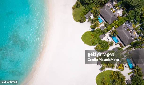 inselresort auf den malediven mit tropischer strandlagune, ferienvillen, palmen und sand von oben gesehen - malediven stock-fotos und bilder