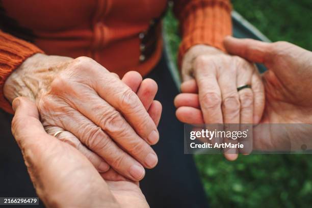 close-up of a man holding an elderly woman's hands - assistente social imagens e fotografias de stock