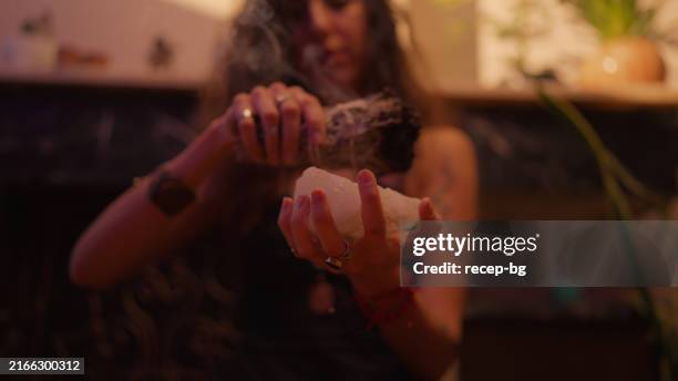 close-up view of woman cleansing crystal gemstone by burning sage bundle - sage stock pictures, royalty-free photos & images