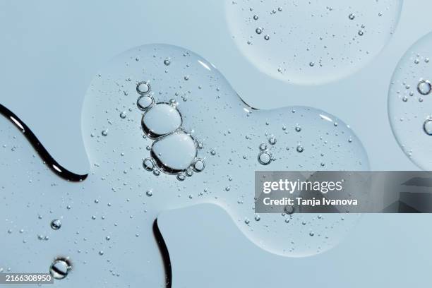 texture of transparent drops of gel or serum with bubbles on blue background. - ácido hialurónico fotografías e imágenes de stock