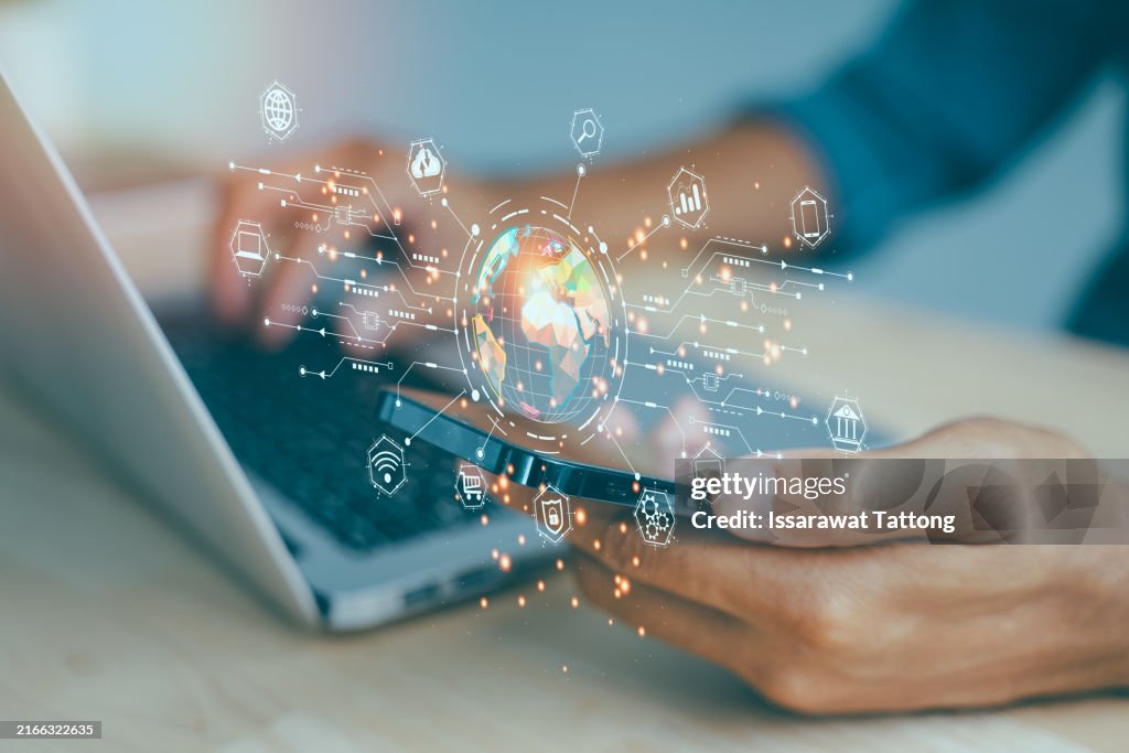 A person is using a laptop and a cell phone