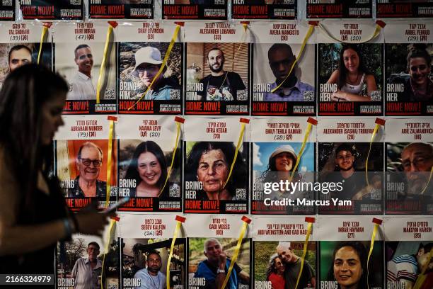 Woman walks past a wall filled with posters for the hostages during a demonstration dubbed ÒLast Chance March!Ó in Tel Aviv, Israel, Thursday, Aug....