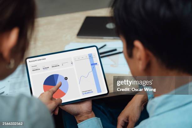 over the shoulder view of young asian couple making financial plan together at home - analysing stock pictures, royalty-free photos & images