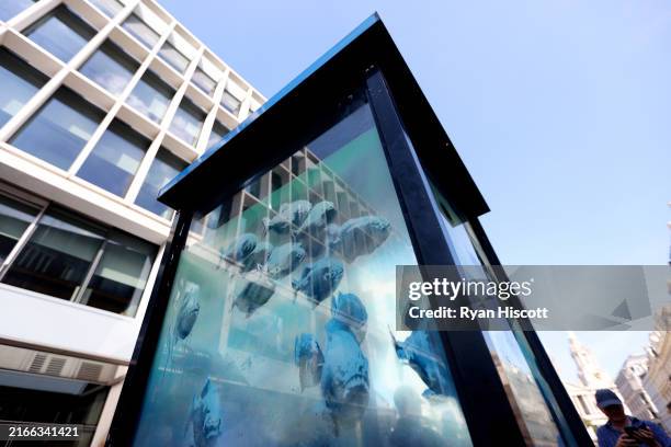 An Artwork featuring a school of fish by Banksy, adorns a City of London Police Box on Ludgate Hill on August 11, 2024 in London, England. The...