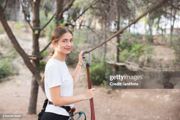 young woman enjoying zip line in the outdoor adventure park with safety harness and climbing equipment. - extreme sports stock pictures, royalty-free photos & images