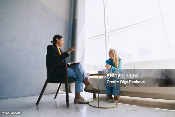 two women sitting in armchairs and talking. female coach, psychotherapist, psychologist, advisor and patient, client, psychotherapy. - saleswoman stock pictures, royalty-free photos & images