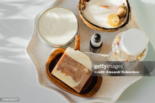 natural skin care. ceramic stand with organic soap, face serum, body cream, relaxing bath salt and candle in coconut. concept of eco-friendly self-care products. flat lay with copy space. high angle view - kuuroord stockfoto's en -beelden