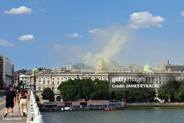 Viewed from Waterloo Bridge, smoke is seen rising into the sky from a fire located in the roof of Somerset House beside the River Thames in London on...