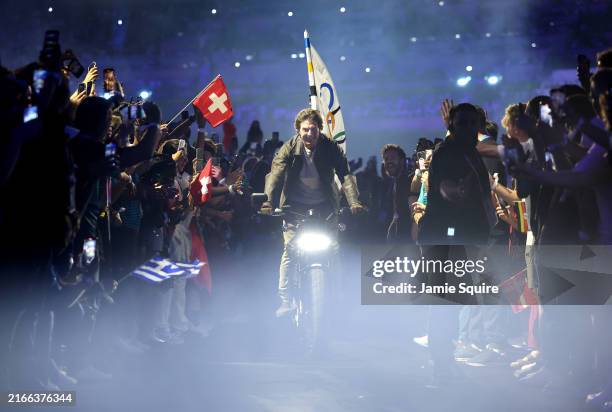 American Actor and Film Producer Tom Cruise rides on a Motorbike with the IOC Flag during the Closing Ceremony of the Olympic Games Paris 2024 at...