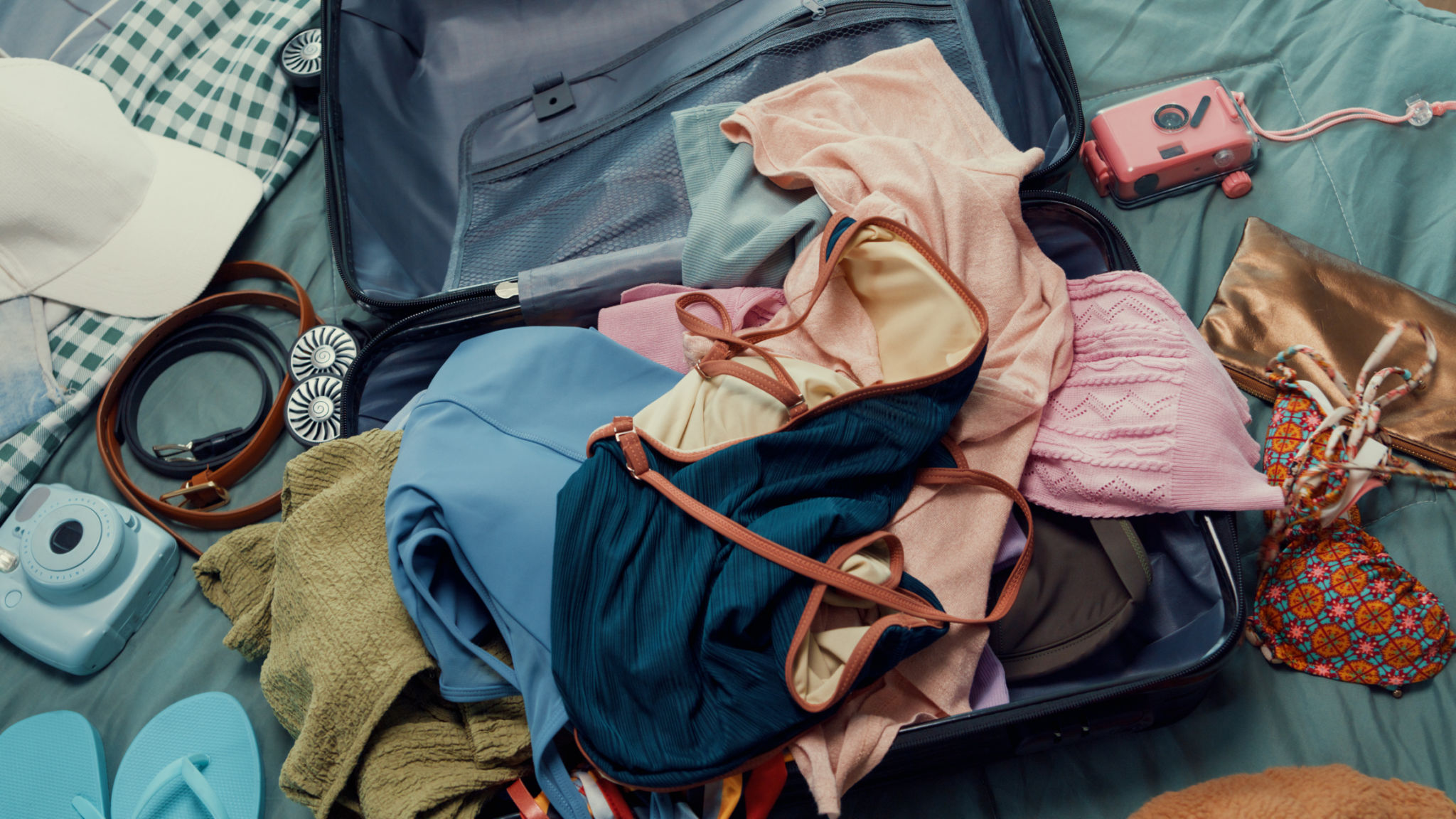 Top view. Young happy and exciting Asian female ready for summer holidays prepare suitcase throw cloth accessories stuff in bag in bedroom. Preparing luggage for summer vacation trip. Top view. Young happy and exciting Asian female ready for summer holidays prepare suitcase throw cloth accessories stuff in bag in bedroom. Preparing luggage for summer vacation trip.