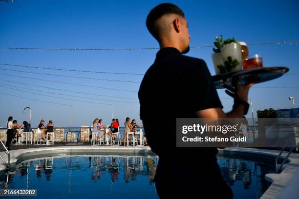 People relax and have a cold drink by a swimming pool on a building during the Daily Life In Andalusia on July 30, 2024 in Malaga, Spain. Andalusia...