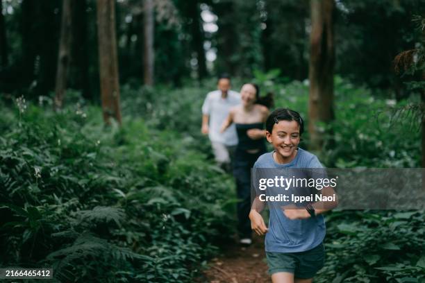 cheerful family running through forest - gedeihend stock-fotos und bilder