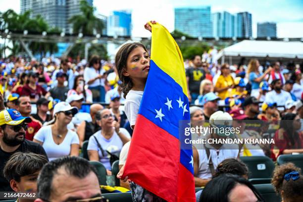 Girl holds the national flag of Venezuela as demonstrators shout slogans during the "Protest for Truth" rally called by the Venezuelan opposition to...